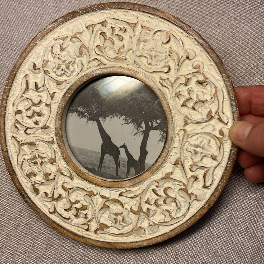 Decorative round, carved wooden picture frame with a distressed white finish.